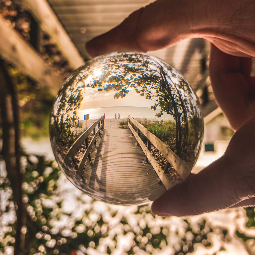 Reflet boule tenue main plage mer nature inspiration coaching orientation Pions jeux bois sur le sol orange jaune vert coaching accompagnement Boussole main hand holding compass orientation formation coaching Peps développement